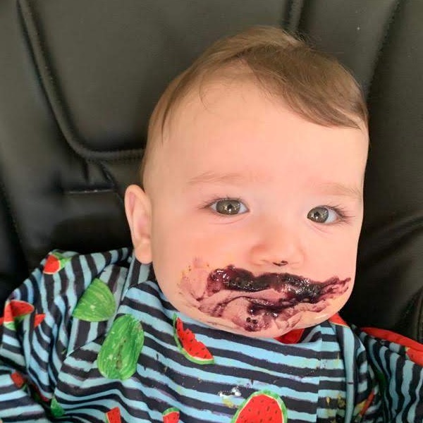 Baby Alex in a high chair with his face covered in food.