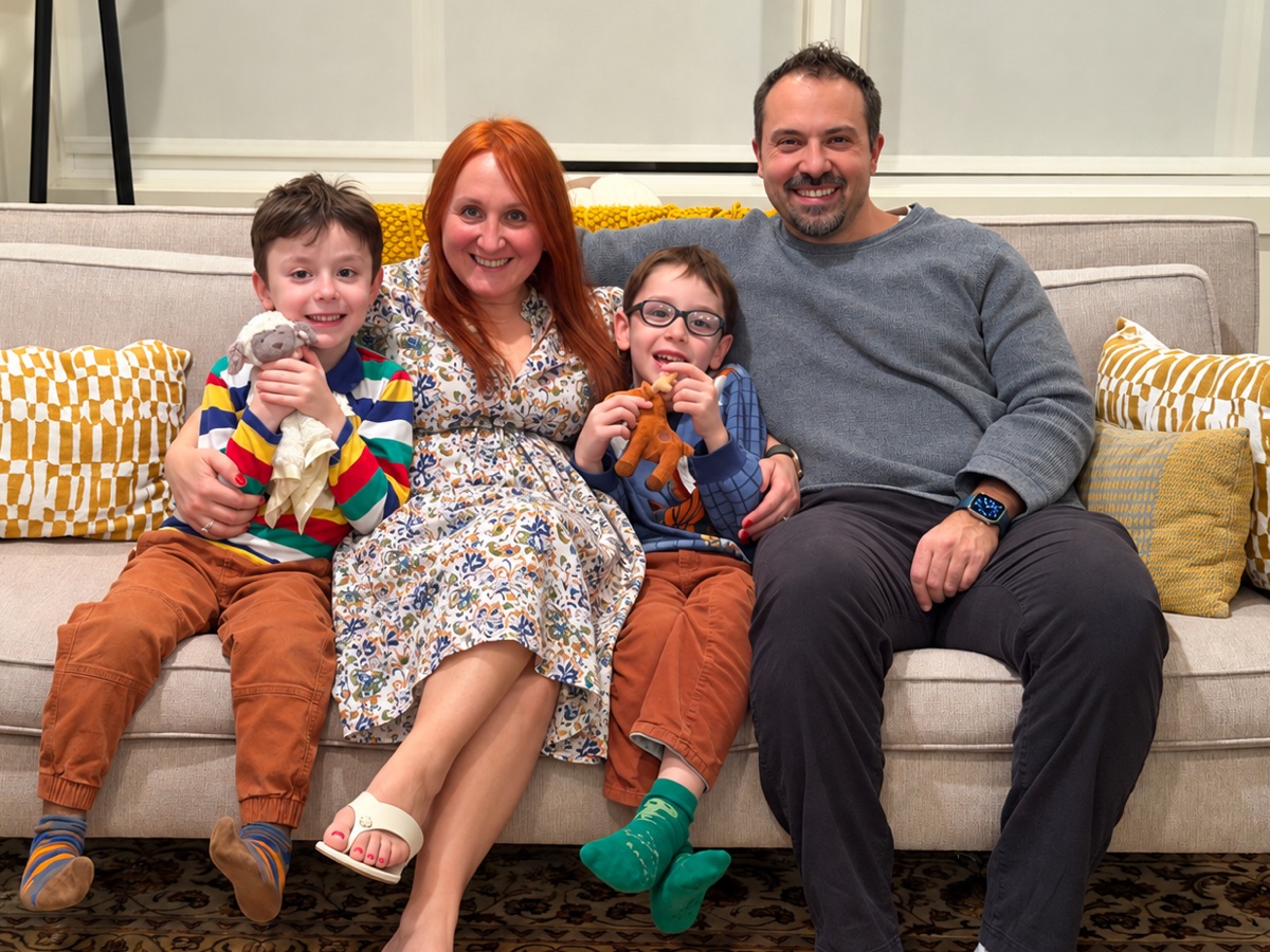 The family on a sofa at home: Niko, Lidia, Alex and Oral, all smiling.
